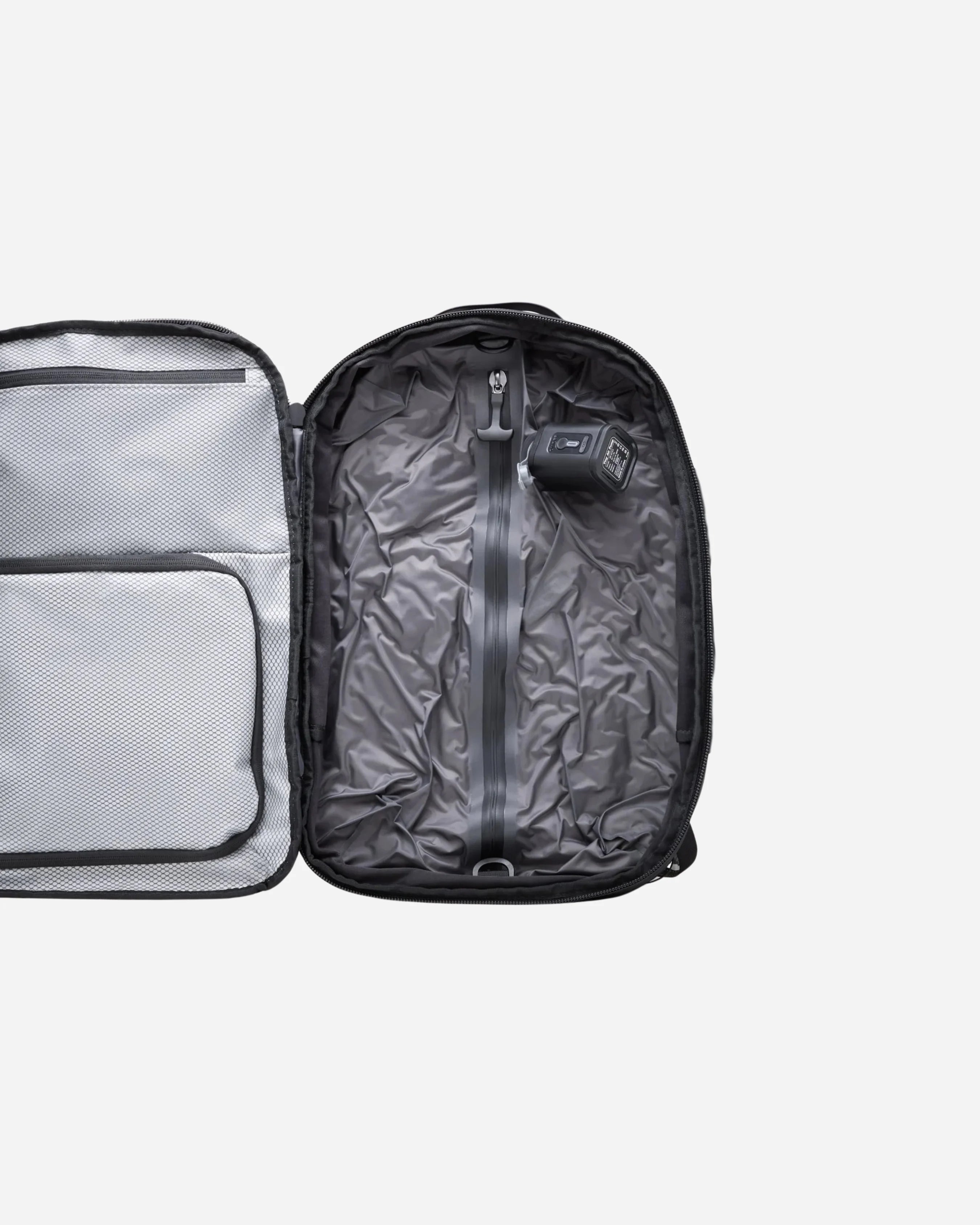 Electric air pump placed inside a travel backpack, showing the included vacuum compression accessory used to remove air and save space.