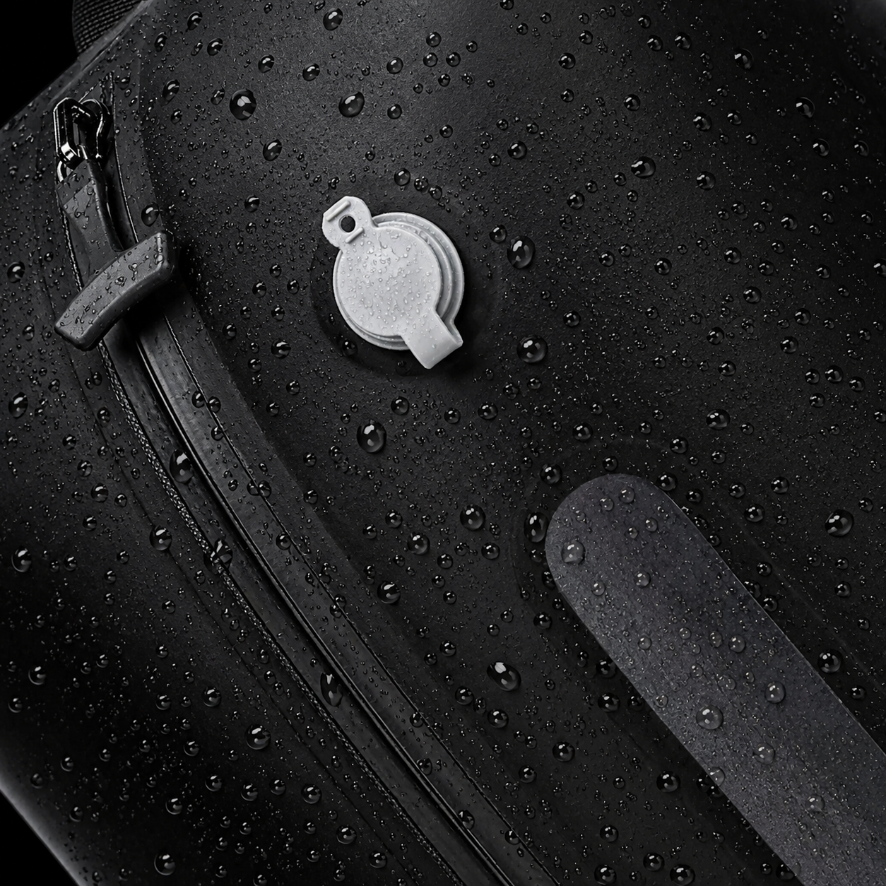 Close‑up of Lavnex Still Vac™ Jet Black vacuum compression bag surface covered with water droplets showing waterproof material and air valve detail