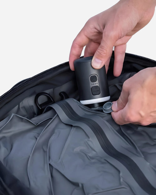 Hands using Lavnex VoxAir Pro™  portable air pump to inflate travel bag or vacuum compartment