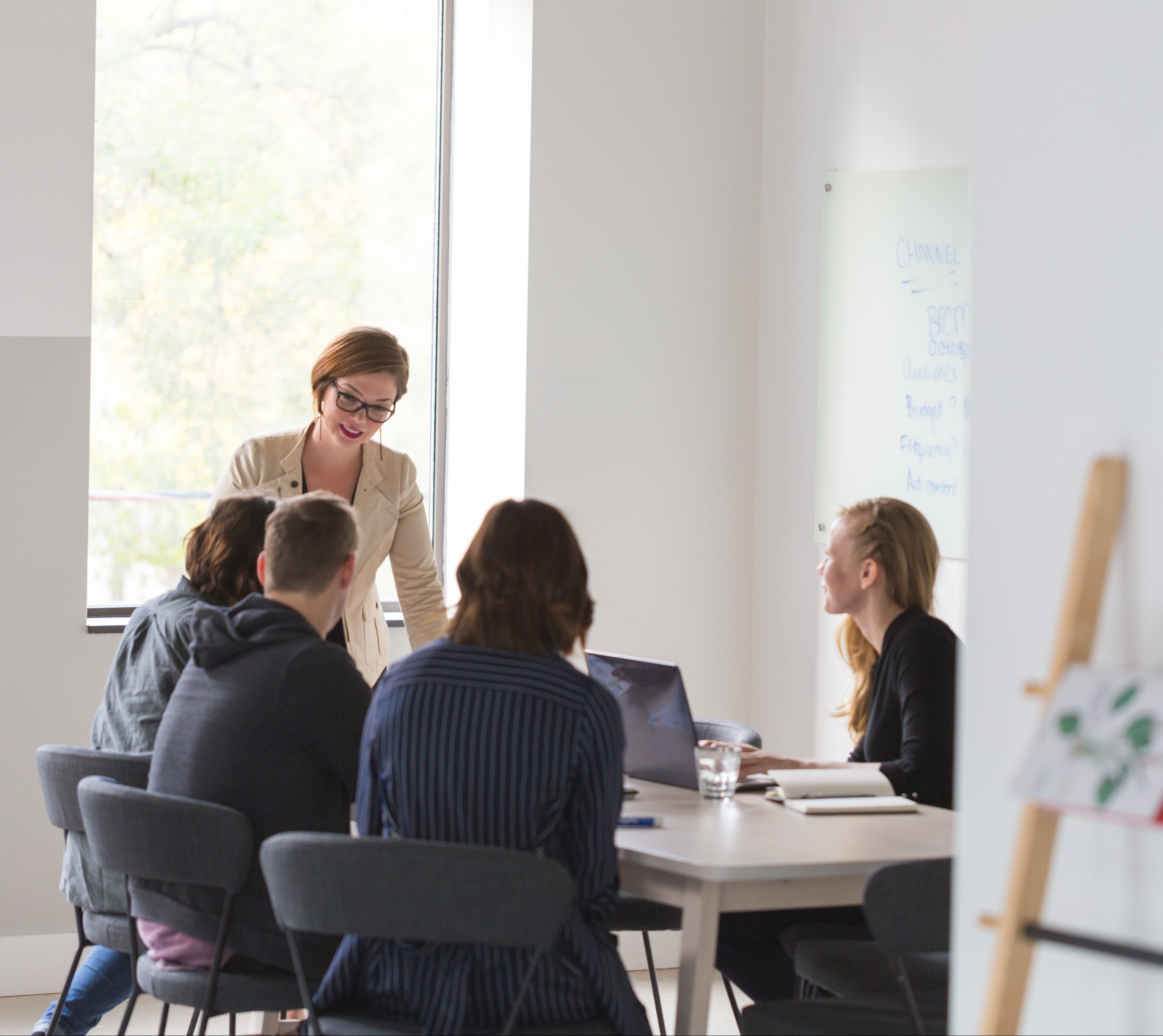 Group of people in a meeting room with a woman standing at the front.